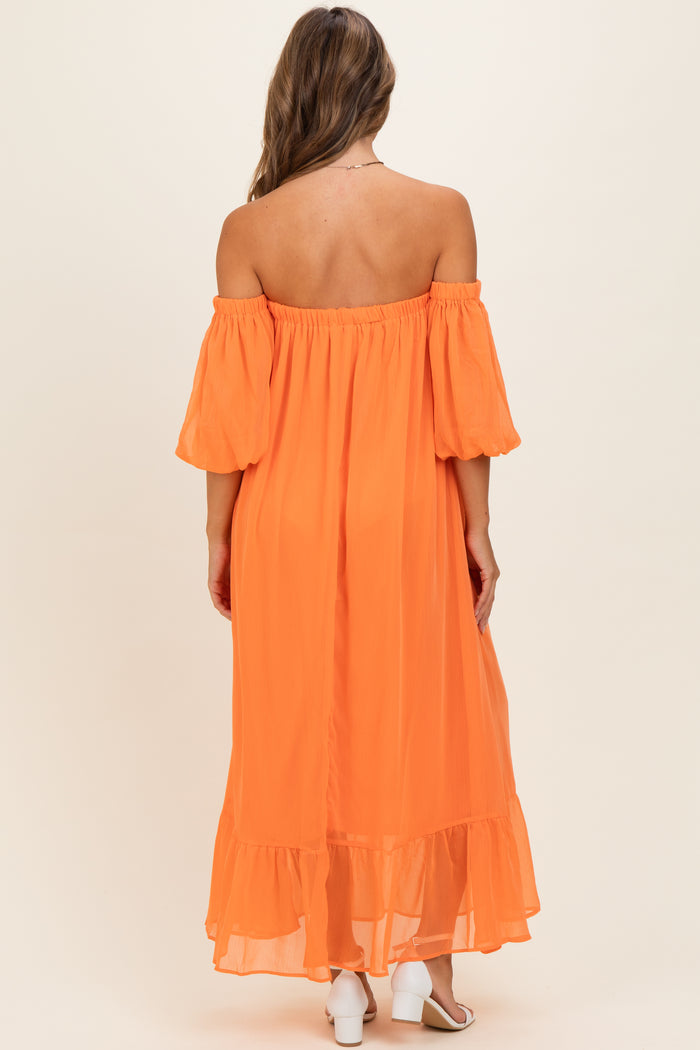 woman wearing an off-shoulder orange maxi dress with puff sleeves and a ruffled hem