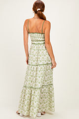woman wearing a green and white floral maxi dress with thin straps and a tiered design, shown from the back