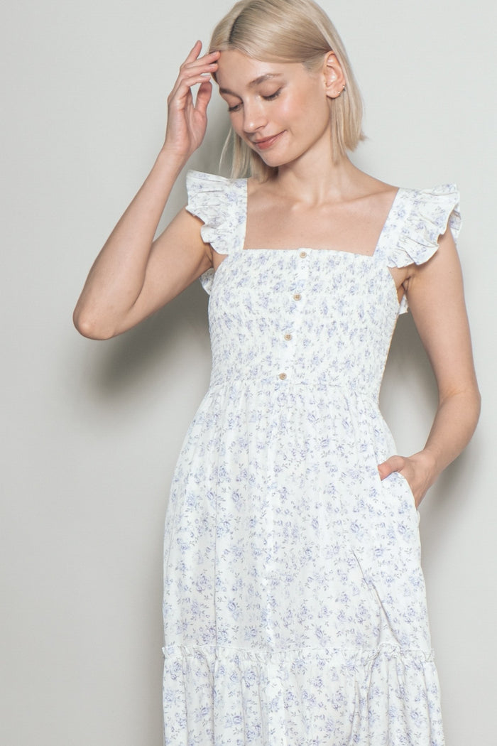 woman wearing a white floral print maxi dress with ruffled shoulder straps and a square neckline