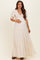 woman wearing a cream maternity maxi dress with puff sleeves and ruffled tiers, holding her baby bump