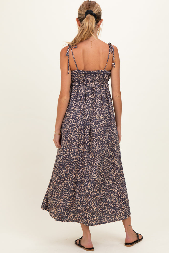 woman wearing a navy floral maternity maxi dress with adjustable straps and a smocked bodice, seen from the back