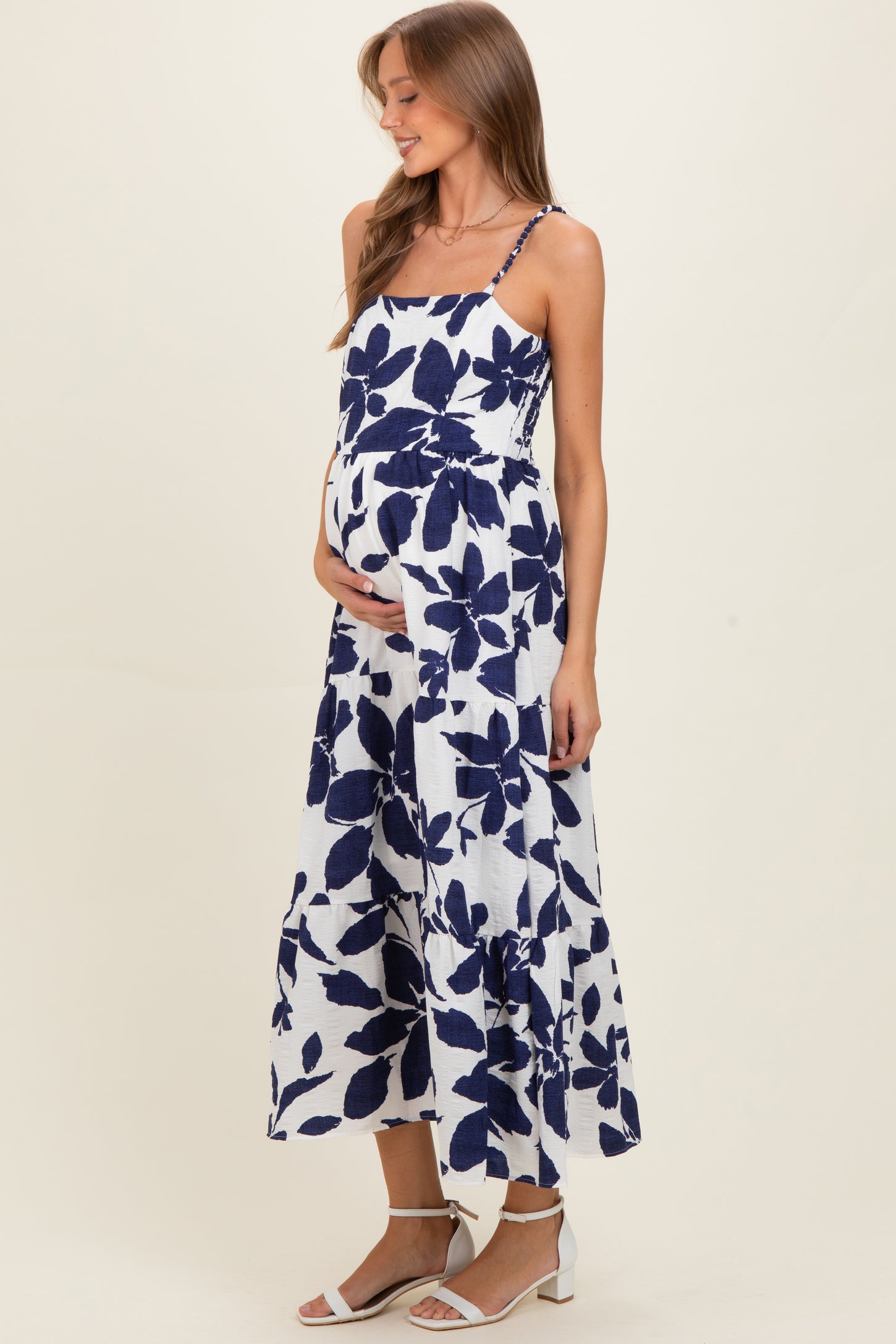 woman wearing a navy and white floral print maternity dress with spaghetti straps and a visible baby bump
