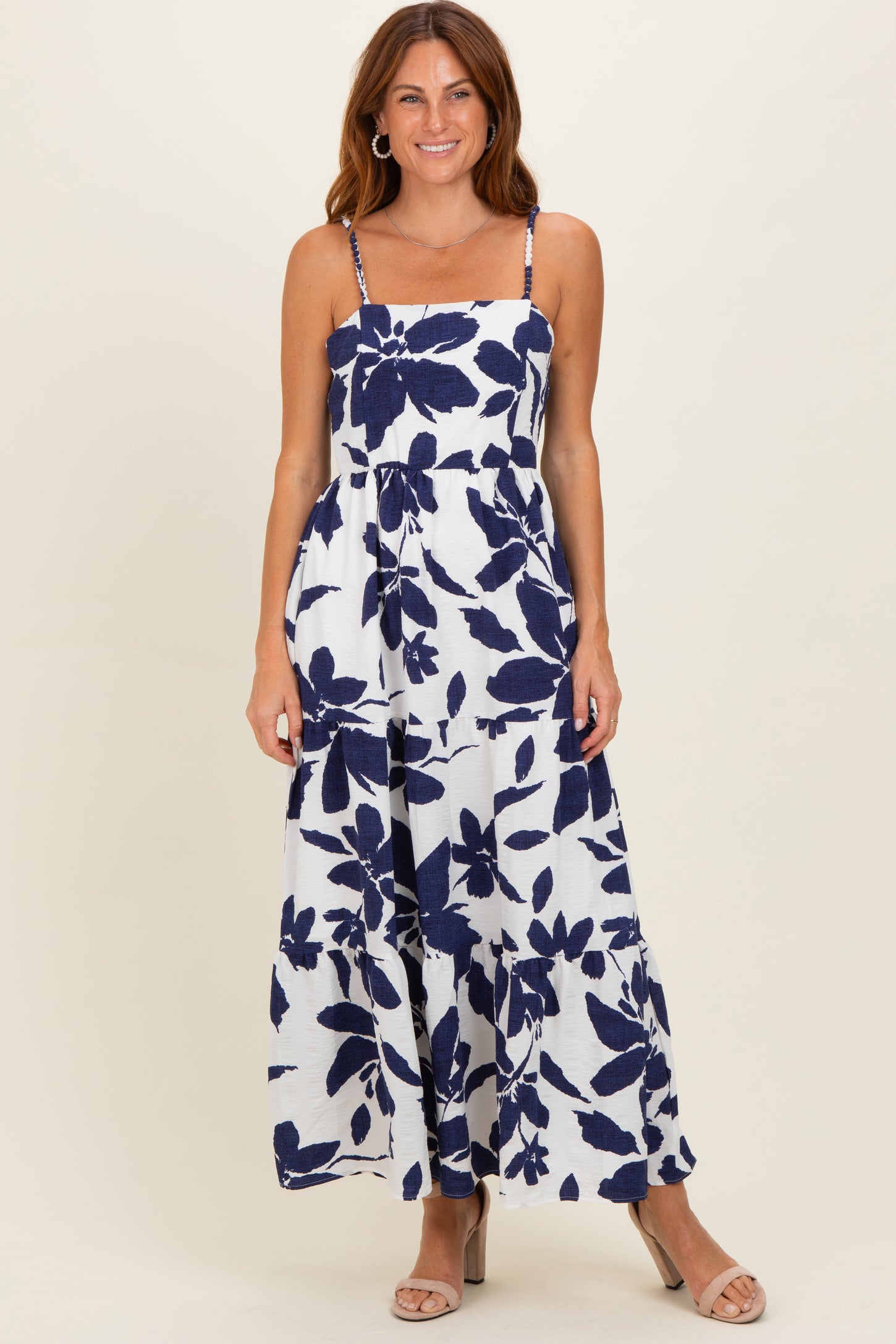 woman wearing a navy and white floral maxi dress with thin spaghetti straps and a flowy silhouette
