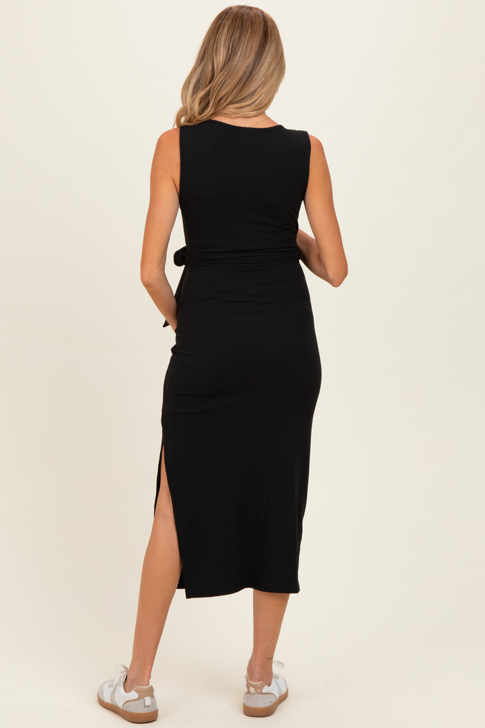 woman wearing a black ribbed maternity midi dress with a tie waist and side slit, showcasing a baby bump from behind
