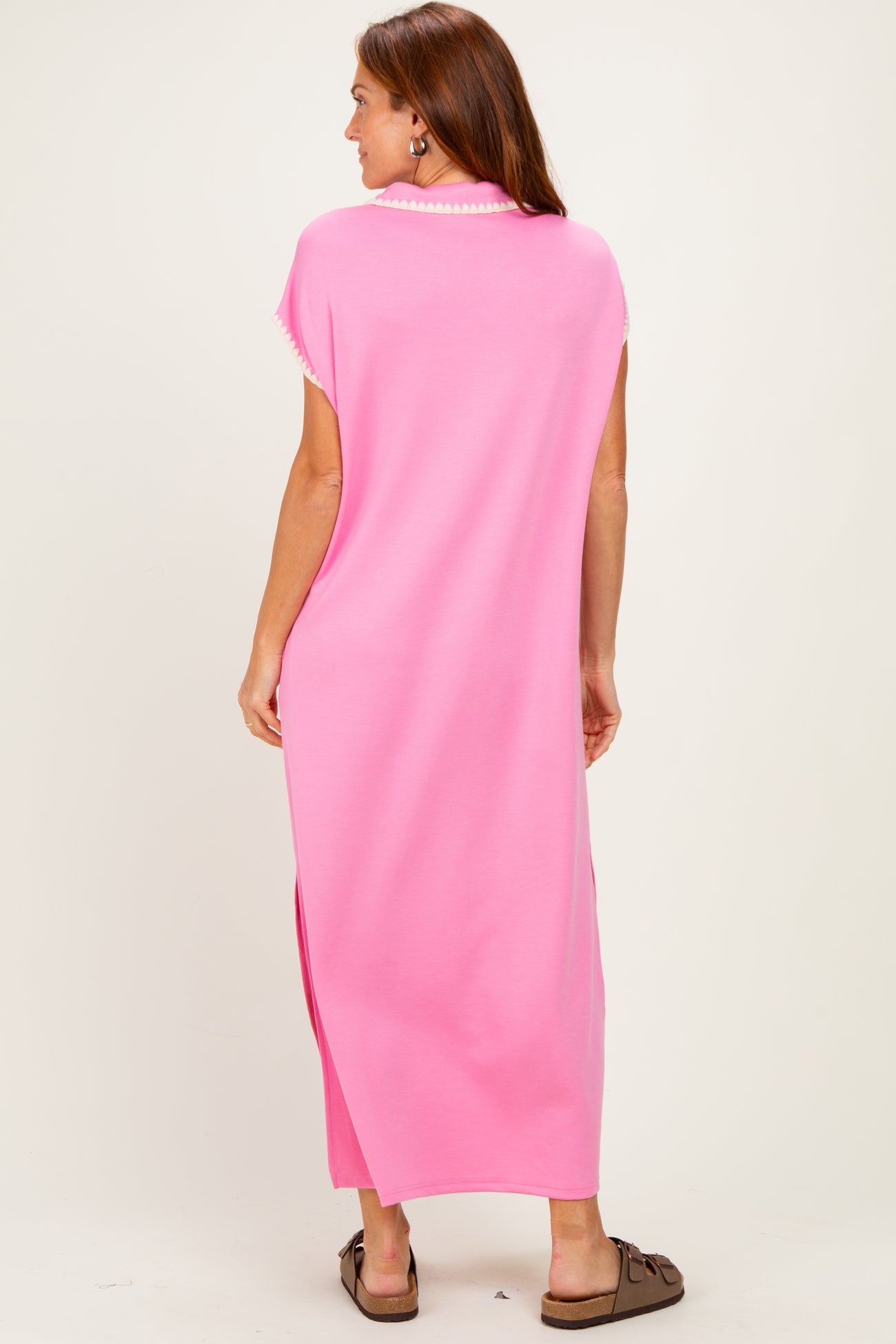woman wearing a long pink maxi dress with side slits and short sleeves, viewed from the back