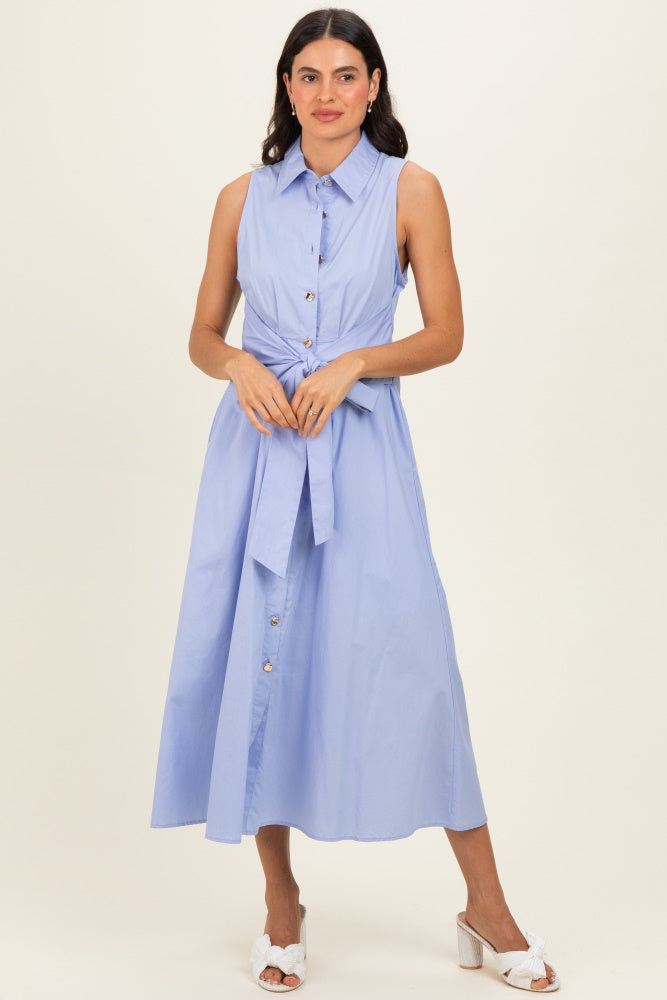 woman wearing a sleeveless light blue button-up dress with a tie waist detail and a flowing skirt