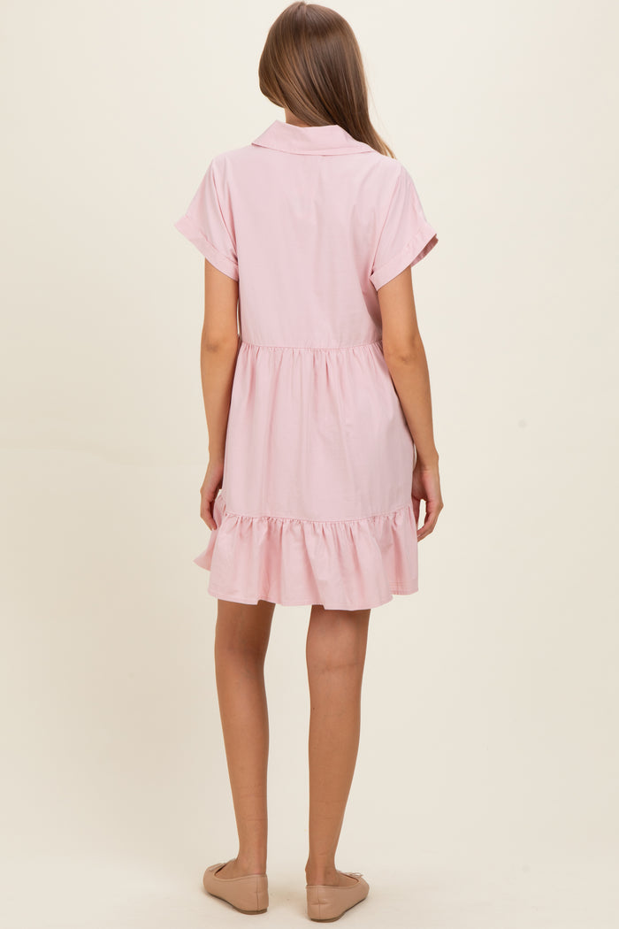 woman wearing a light pink short sleeve maternity dress with a ruffled hem and a button-up collar