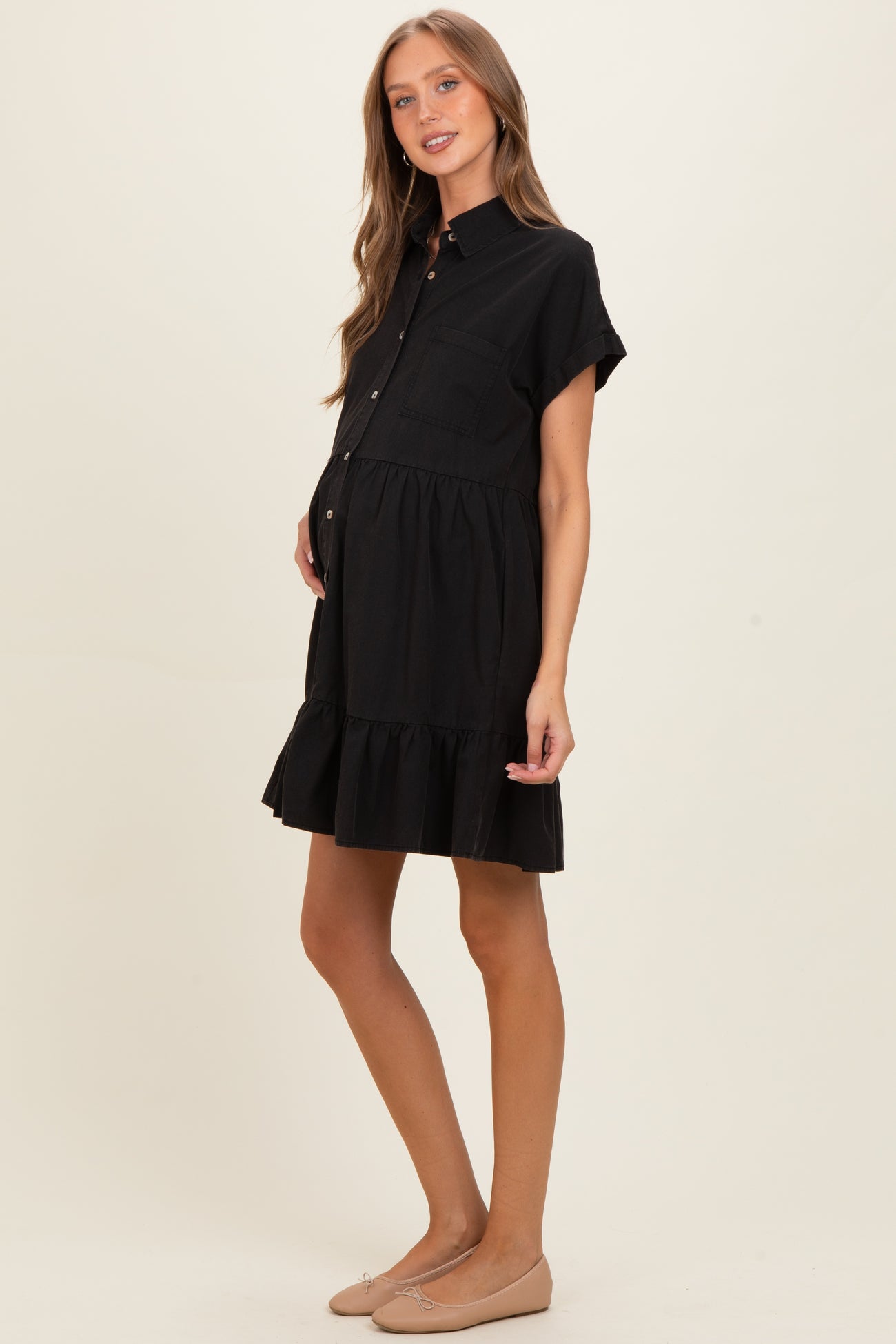 woman wearing a black maternity button-up dress with a tiered ruffle hem and a visible baby bump