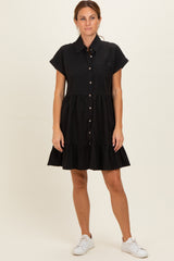 woman wearing a black short sleeve button-up dress with a tiered skirt and side pockets, styled with white sneakers