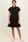 woman wearing a black short sleeve button-up dress with a tiered skirt and side pockets, styled with white sneakers