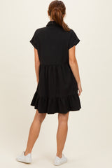 woman wearing a black short sleeve tiered dress with a collar and white sneakers, viewed from the back