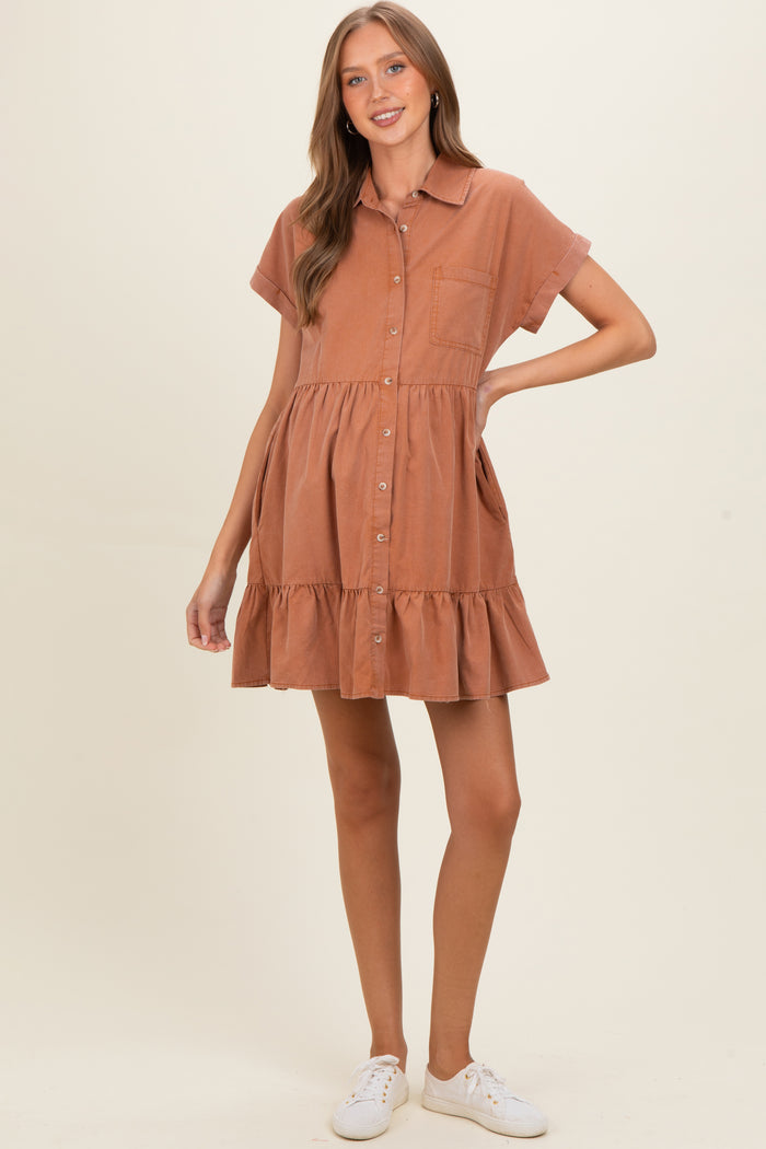 woman wearing a rust-colored short sleeve maternity dress with a button front and ruffle hem