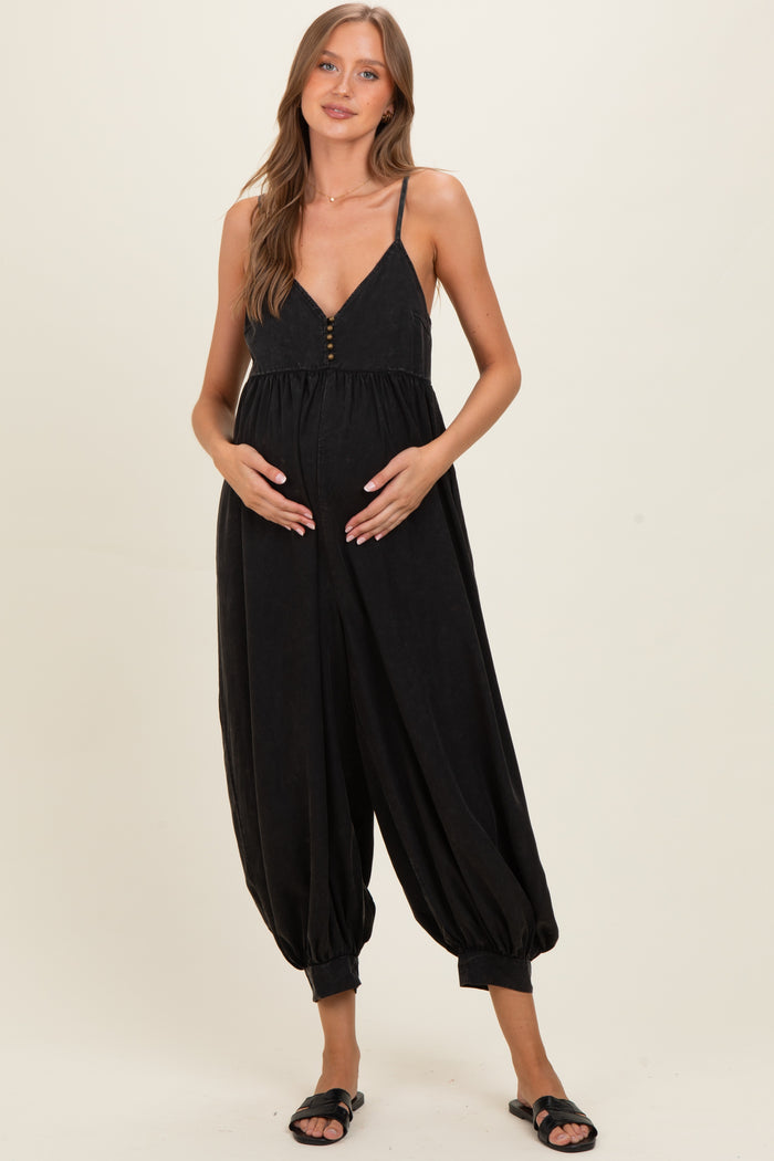 woman wearing a black maternity jumpsuit with a button-up front and balloon-style legs, holding her baby bump
