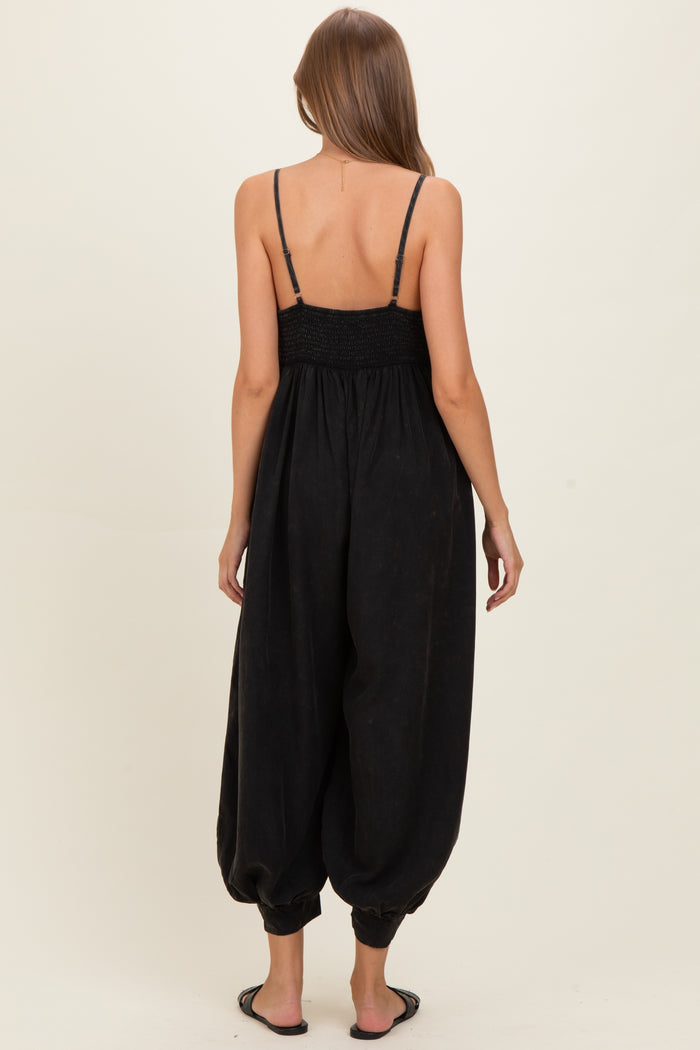 woman wearing a black maternity jumpsuit with a smocked back and loose, tapered legs
