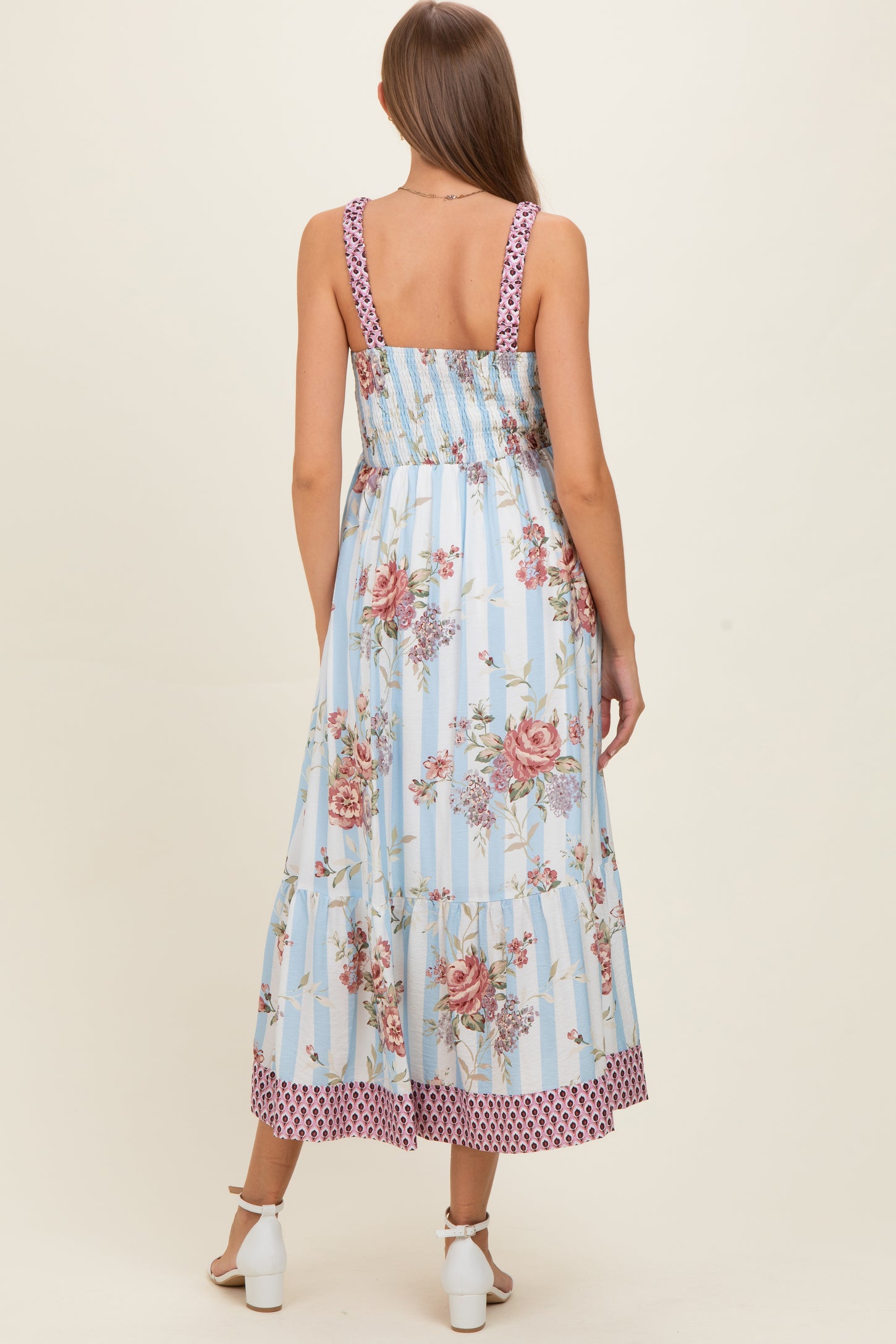 woman wearing a blue floral maxi maternity dress with a smocked back and polka dot trim, showing a baby bump