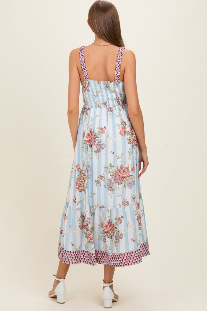 woman wearing a blue floral maxi maternity dress with a smocked back and polka dot trim, showing a baby bump
