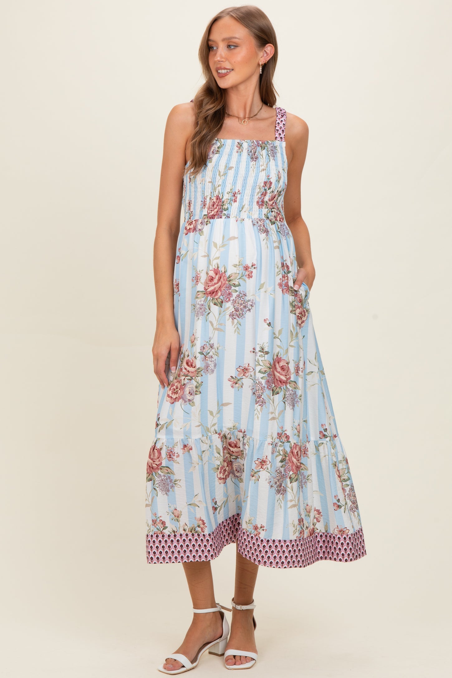 woman wearing a blue floral maternity maxi dress with smocked bodice and pockets