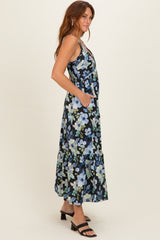 woman wearing a black floral maxi dress with pockets and a tiered skirt, standing sideways with a relaxed pose