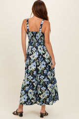 woman wearing a navy blue floral maxi dress with smocked back and tiered skirt, standing with back toward the camera