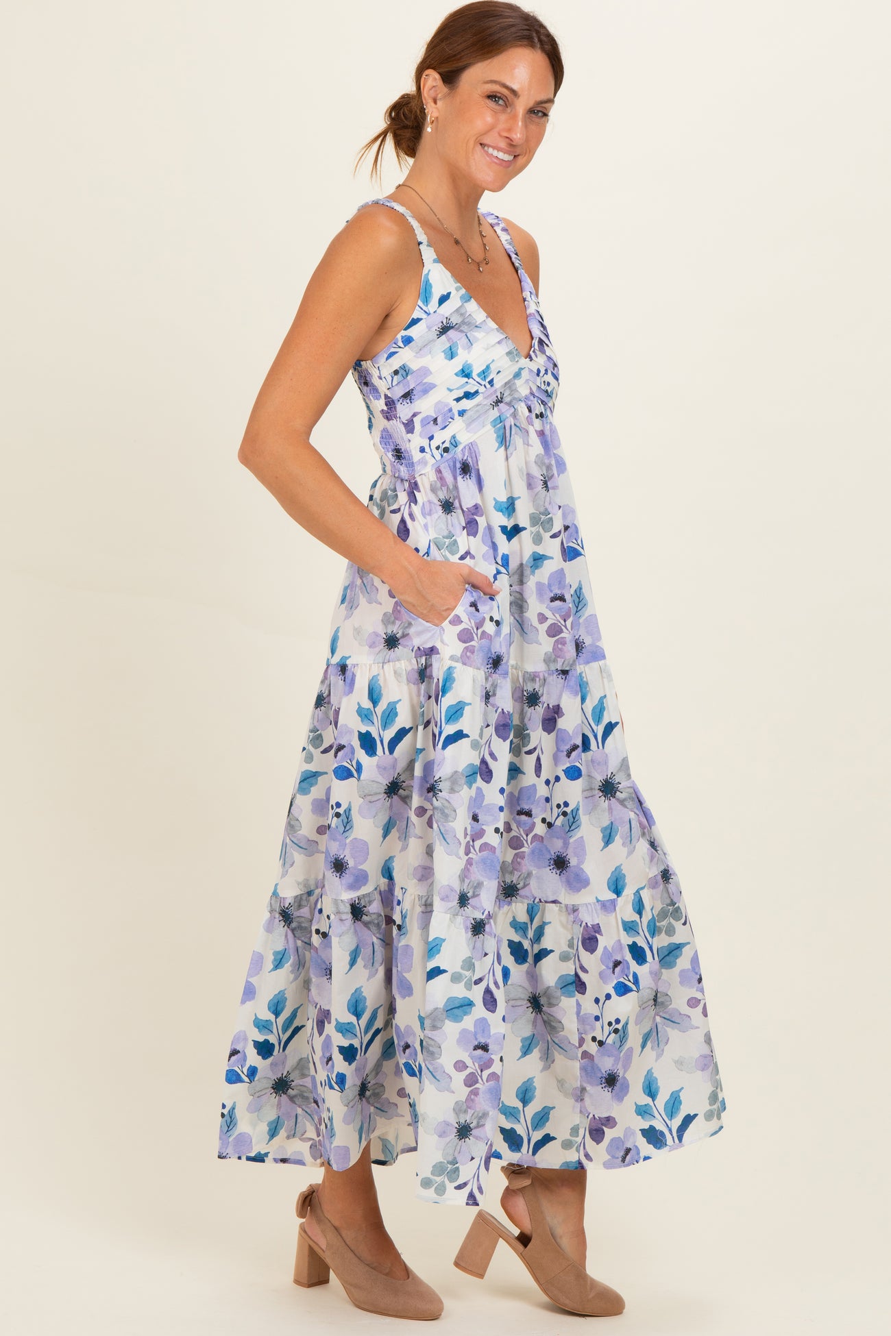 woman wearing a floral maxi dress with purple and blue patterns, featuring a v-neck and pockets