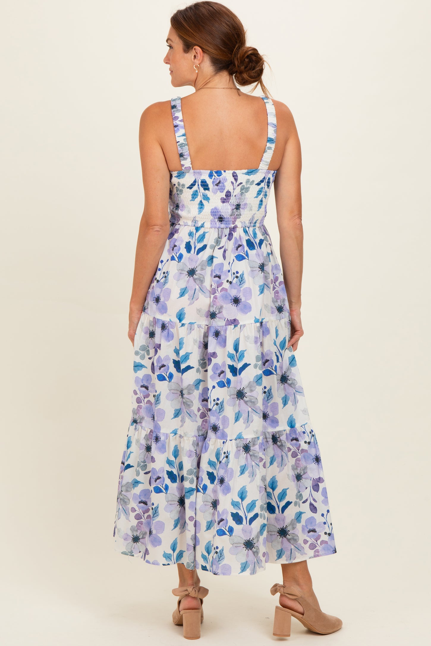 woman wearing a floral print maxi dress with a smocked bodice and tiered skirt, viewed from the back