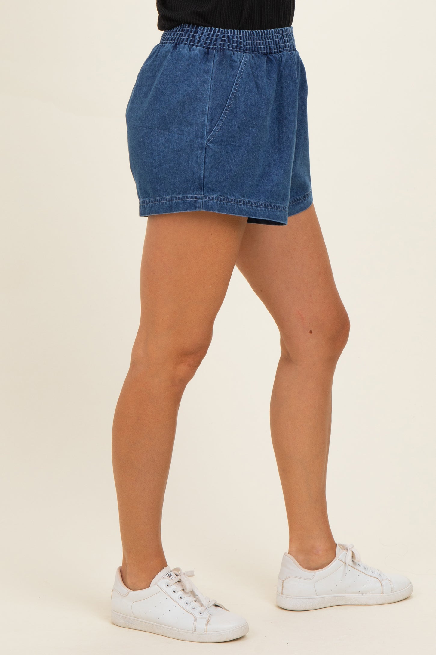 woman wearing dark denim shorts with an elastic waistband and side pockets