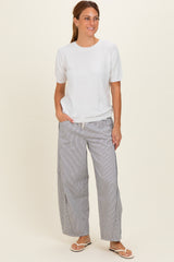 woman wearing a white short sleeve top and striped wide-leg pants, standing and smiling