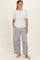 woman wearing a white short sleeve top and striped wide-leg pants, standing and smiling