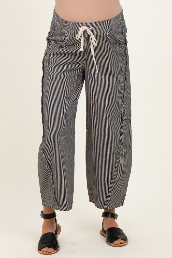 woman wearing black and white striped maternity pants with a drawstring waist and cropped length, showcasing her baby bump