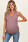 woman wearing a mauve maternity tank top with a v-neck and showing her baby bump while smiling
