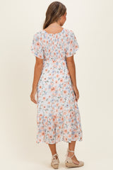 woman wearing a floral midi dress with short sleeves and a tiered skirt, shown from the back