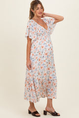 woman wearing a floral print maternity dress with a v-neckline and flutter sleeves, showcasing her baby bump