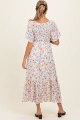 woman wearing a floral print maternity dress with short sleeves and a tiered hem, showcasing a baby bump