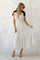 woman wearing a white polka dot maxi dress with a v-neckline and tiered skirt, standing against a textured background