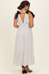 woman wearing a white polka dot maternity maxi dress with a back v-neck and tie straps
