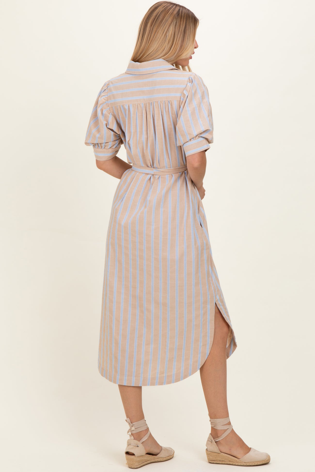 woman wearing a beige and blue striped button-up midi dress with short sleeves and a tie belt, shown from the back