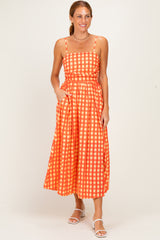 woman wearing an orange and white checked maxi dress with adjustable straps and pockets