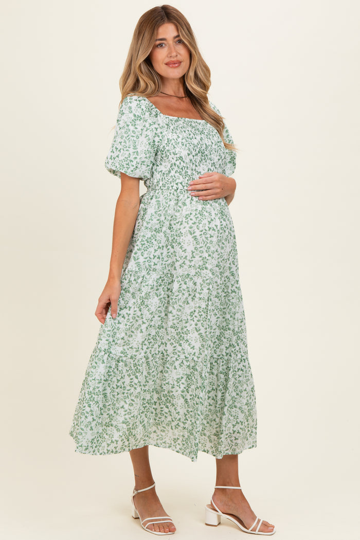 woman wearing a green floral maternity dress with puff sleeves and a baby bump visible