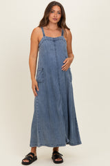 woman wearing a blue denim maternity maxi dress with pockets and a baby bump visible