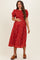 woman wearing a red floral maternity dress with short puff sleeves and a smocked bodice, holding her baby bump