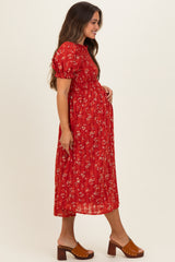 woman wearing a red floral maternity dress with puff sleeves and a smocked bodice, gently cradling her baby bump