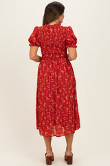 woman wearing a red floral maternity dress with puff sleeves and smocked back, showing a flowy mid-calf length