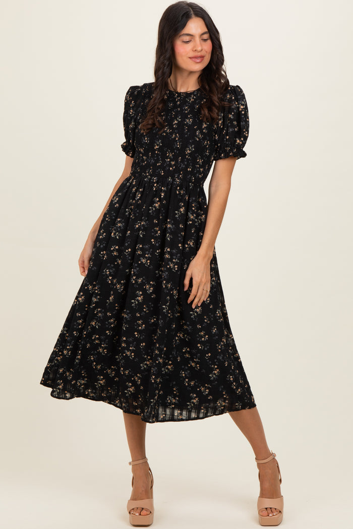 woman wearing a black floral puff sleeve midi dress with a smocked bodice and a flowing skirt