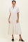 woman wearing a cream striped midi dress with short sleeves and a drawstring waist, paired with black slide sandals