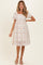 woman wearing a floral maternity dress with short puff sleeves and a square neckline, standing on a light background