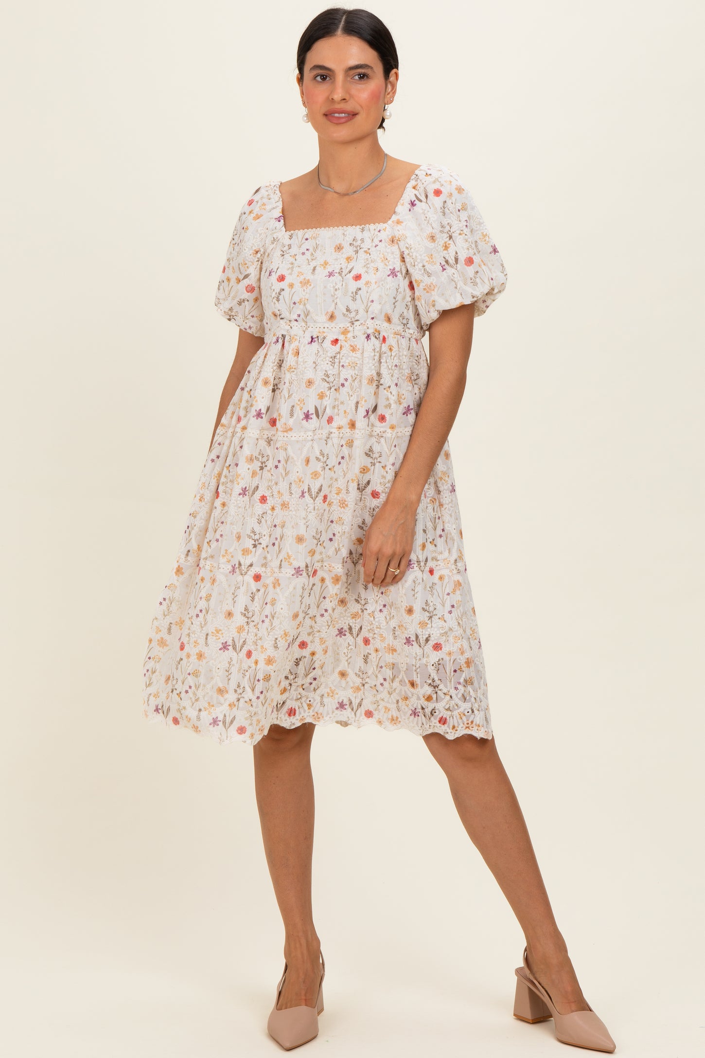 woman wearing a white floral embroidered short sleeve dress with a square neckline and puff sleeves
