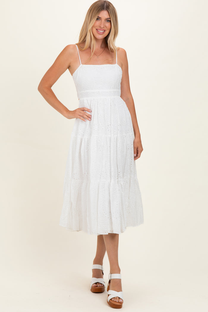 woman wearing a white tiered midi dress with spaghetti straps and eyelet lace details