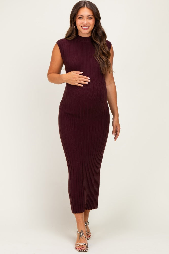 woman wearing a burgundy sleeveless ribbed maternity dress and gently cradling her baby bump
