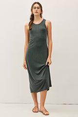 woman wearing a dark green sleeveless midi dress and holding the hem while standing against a plain background