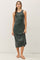 woman wearing a dark green sleeveless midi dress and holding the hem while standing against a plain background